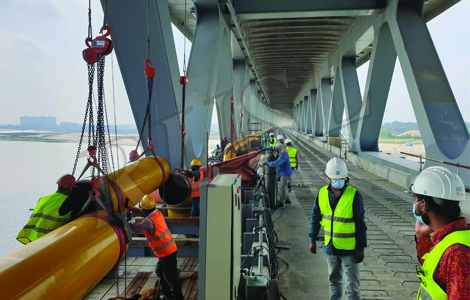 Crew in helmets and high-visibility vests installing the gas transmission pipeline on the Padma Multipurpose Bridge